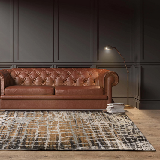 Brown leather sofa in a room with dark paneled walls and a giraffe spot patterned rug.