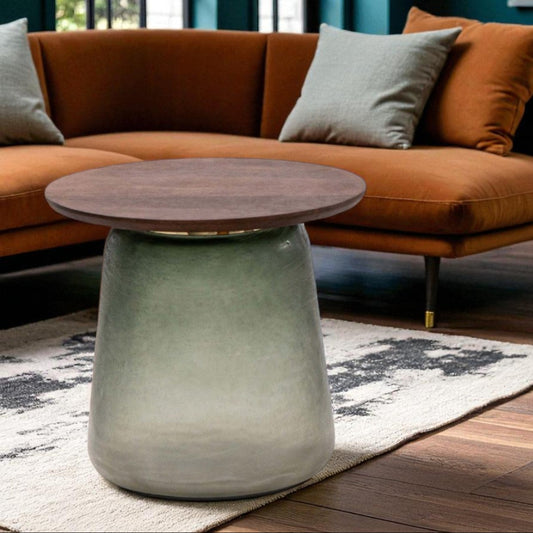 Round wooden table in front of a brown sofa with gray cushions in a living room setting.