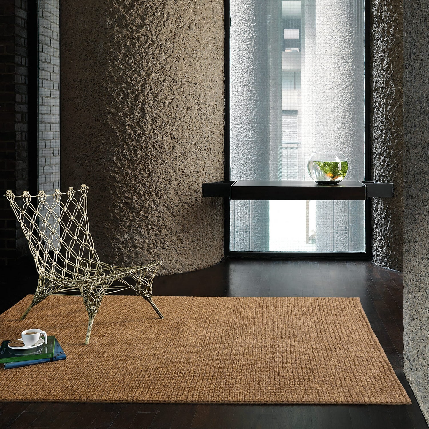 Modern interior with a textured wall, woven chair, and textured rug.