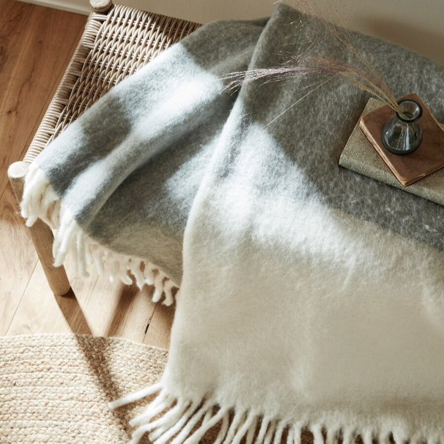 Gradient throw blanket with white and gray colors draped over a wooden surface.