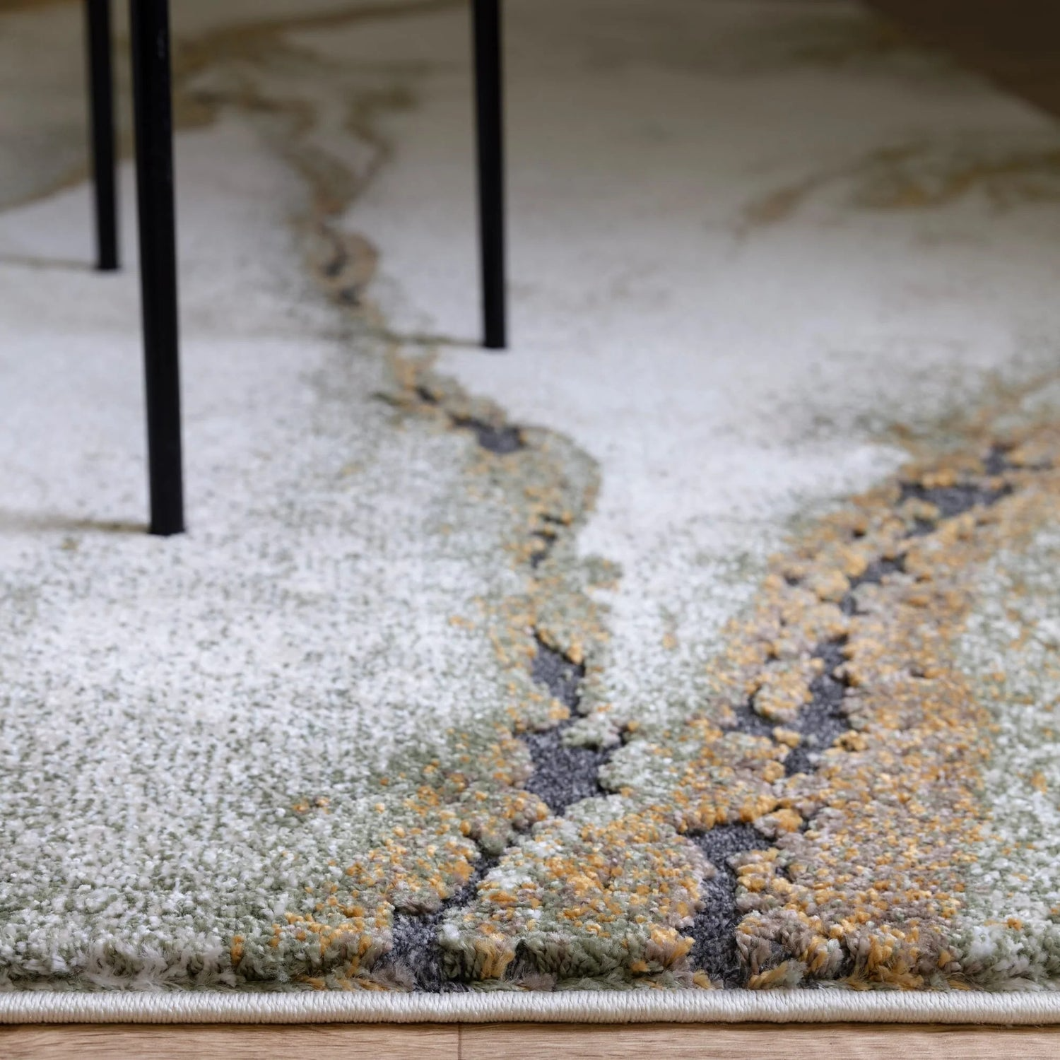 Close-up of a textured area rug with a marbled pattern on a wooden floor.