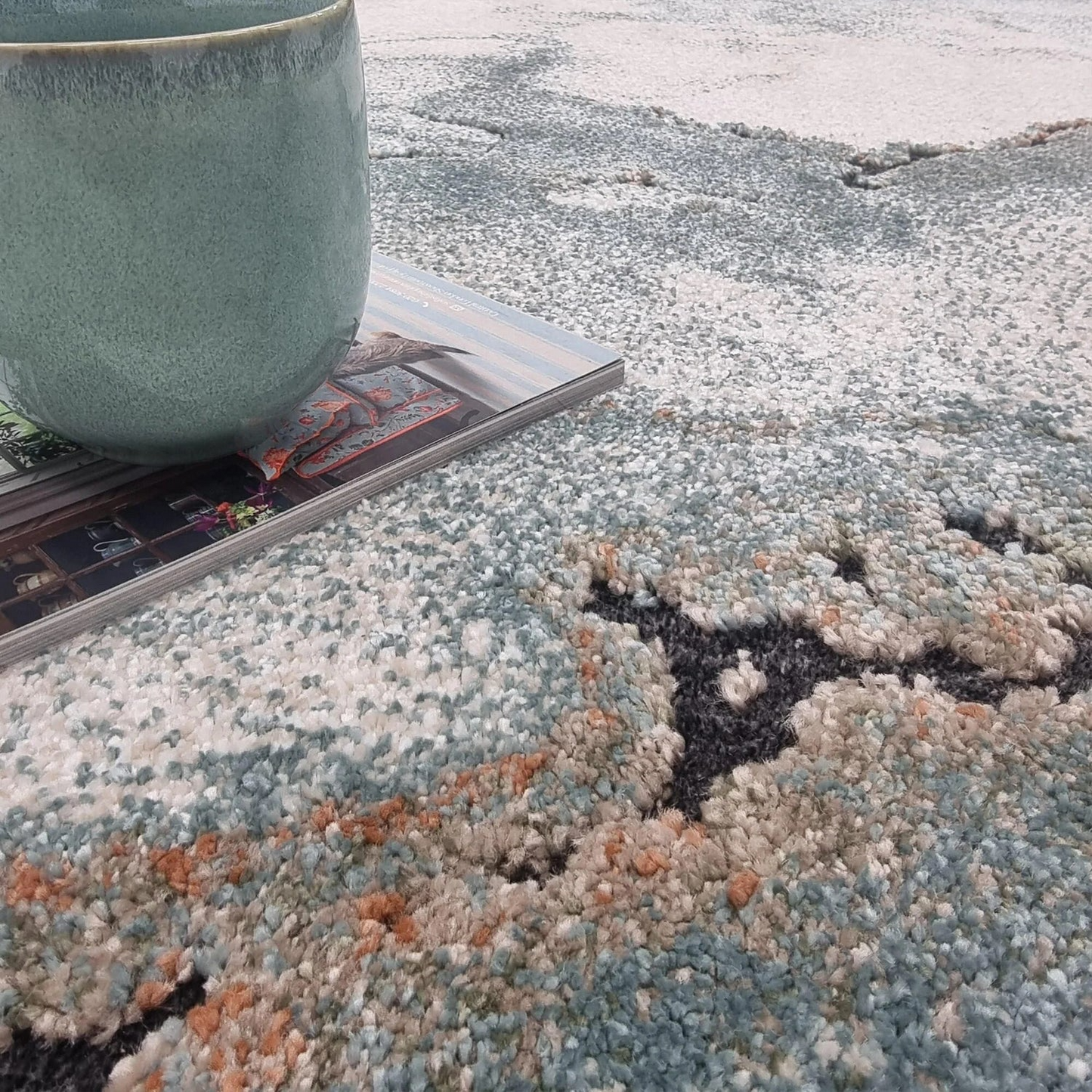 Teal mug on a textured rug with a marbled design