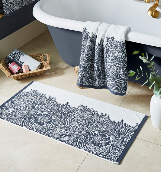 Bathroom setting with a patterned bath mat, towel, and basket near a bathtub.