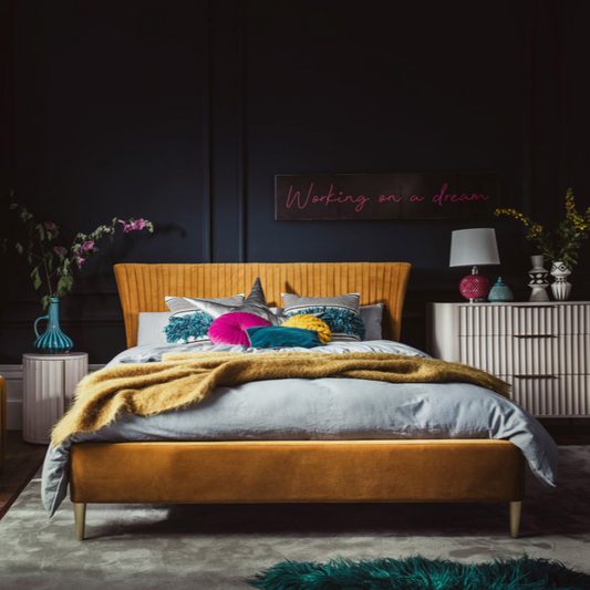 Modern bedroom with a mustard yellow bed and decorative elements.