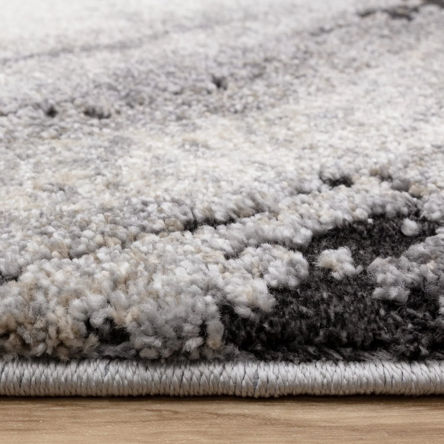 Close-up of a textured gray and white rug on a wooden floor.