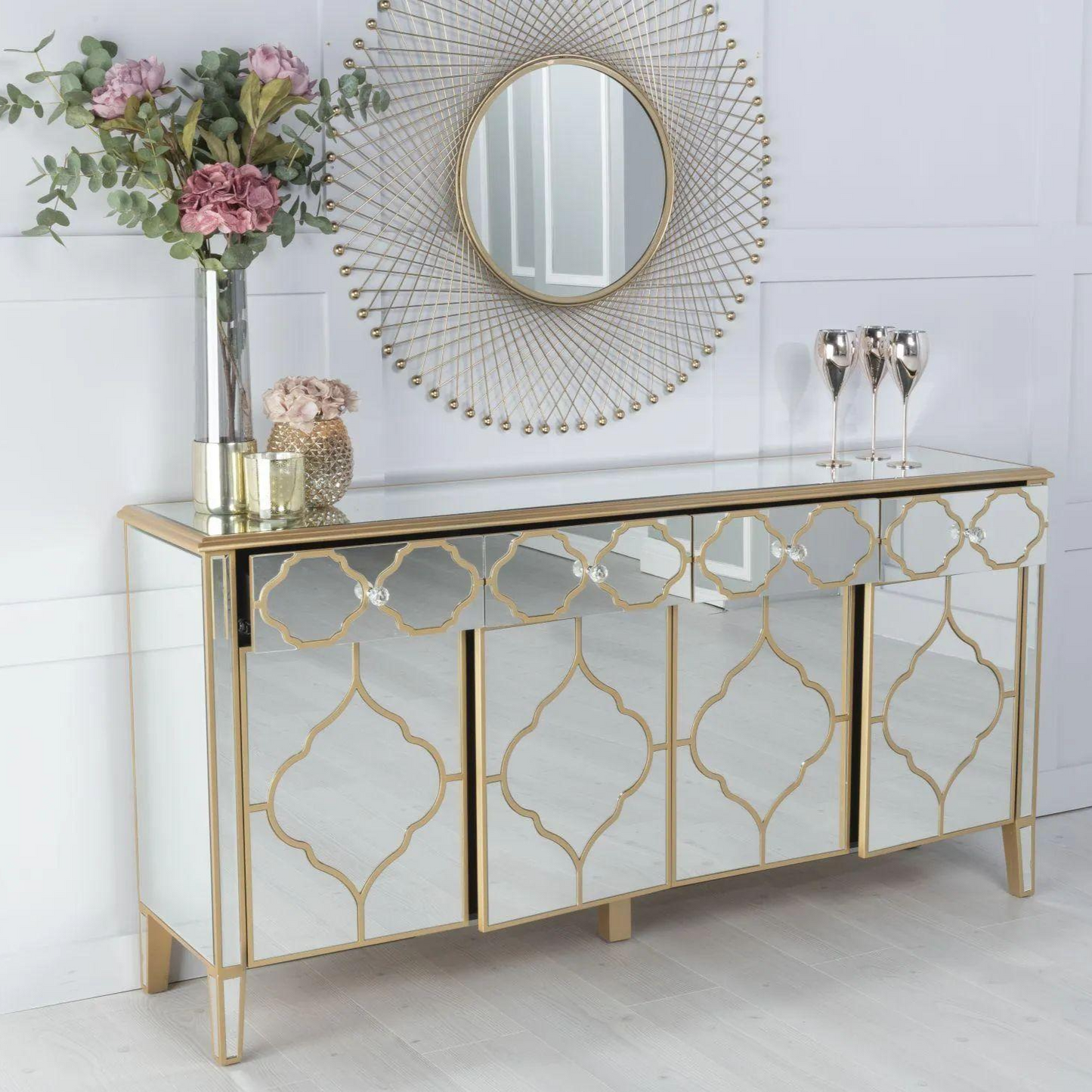 Decorative sideboard with gold geometric patterns, mirror, and flowers in a room.