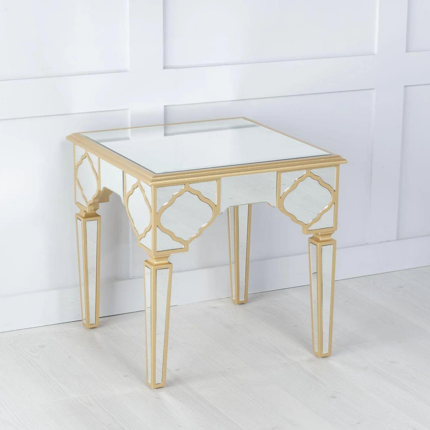 Gold-framed glass table against a white paneled wall