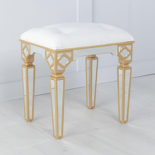 Stool with white cushion and gold metal legs on a white background