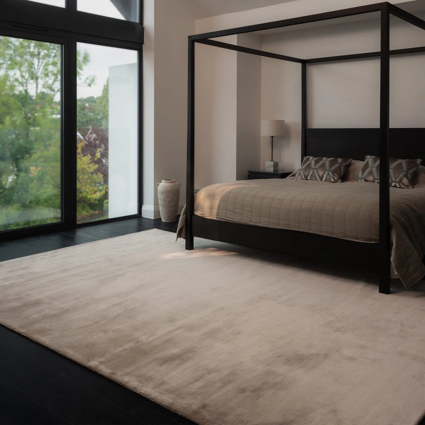 Modern bedroom with a four-poster bed and large windows.