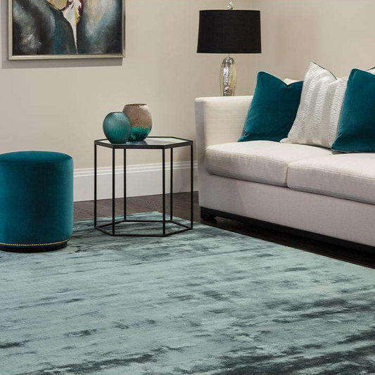 Living room with a white sofa, teal cushions, and a blue rug.