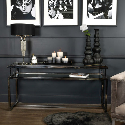Console table with decorative items against a dark wall with framed black and white photos.
