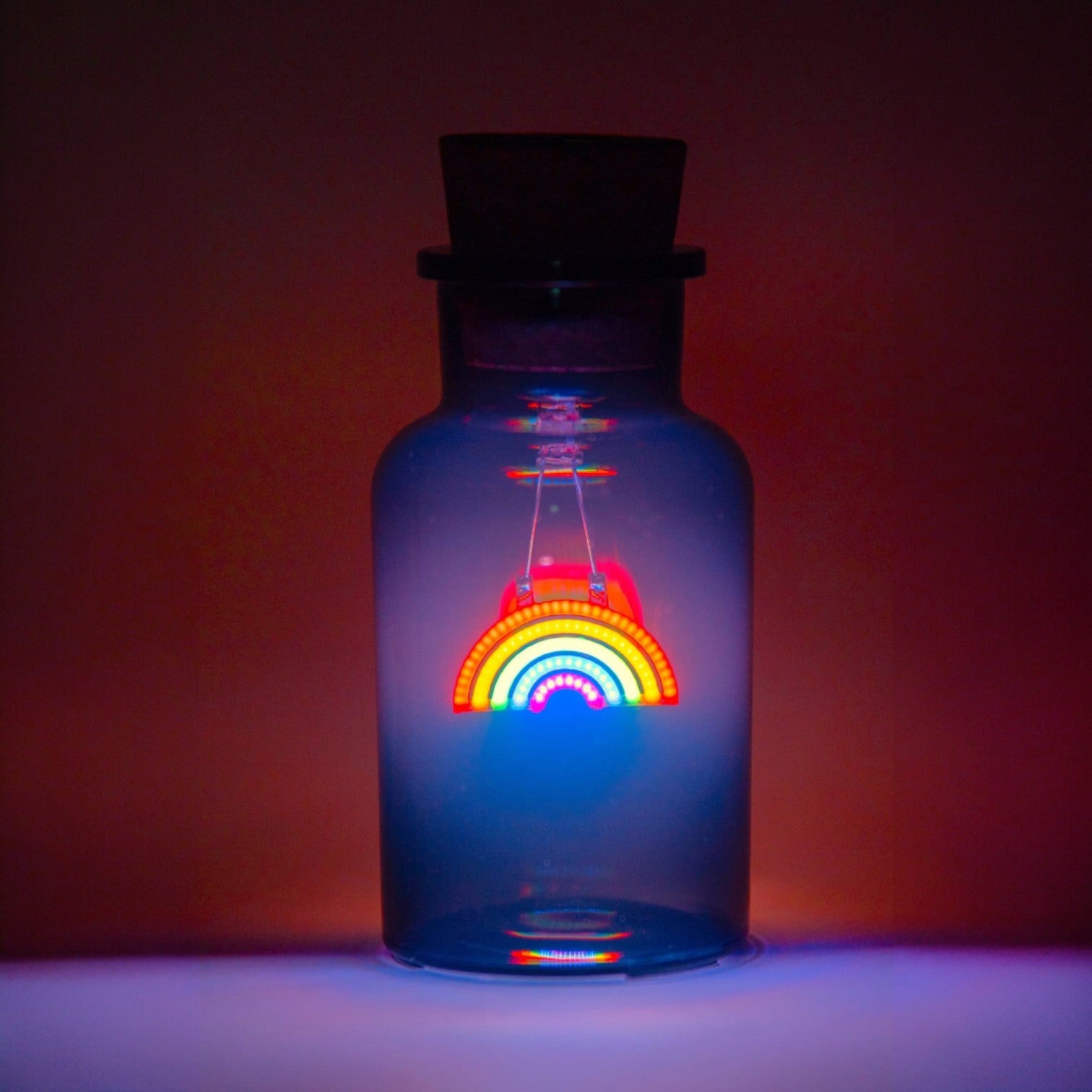 Glass bottle with a colorful rainbow light inside against a dark background