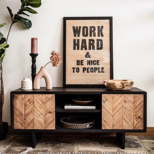 Wooden entertainment console with decorative items and a motivational poster in a living room setting.