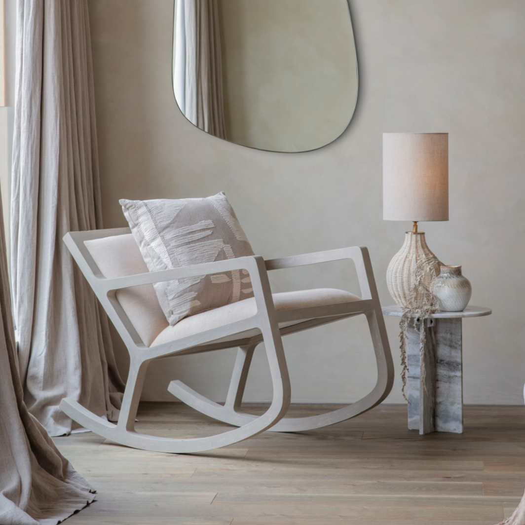 Rocking chair with a lamp and mirror in a room with neutral decor