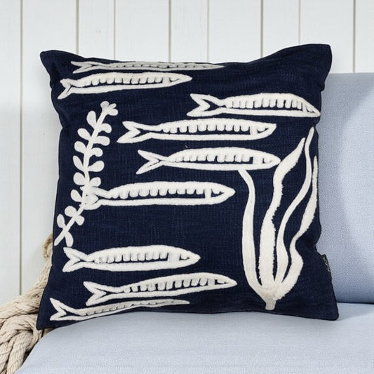 Navy pillow with white fish pattern on a light blue couch.