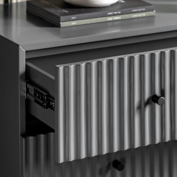 Close-up of a grey cabinet with ribbed design and a knob.