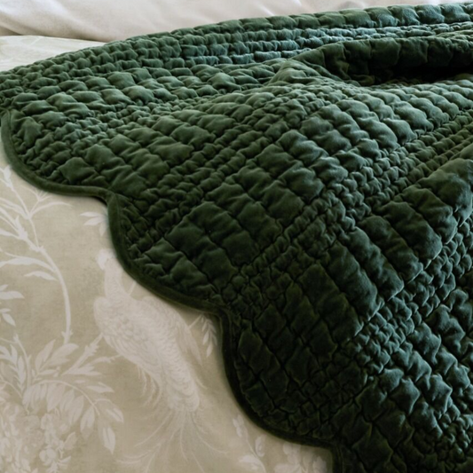 Green quilted blanket on a floral-patterned bedspread