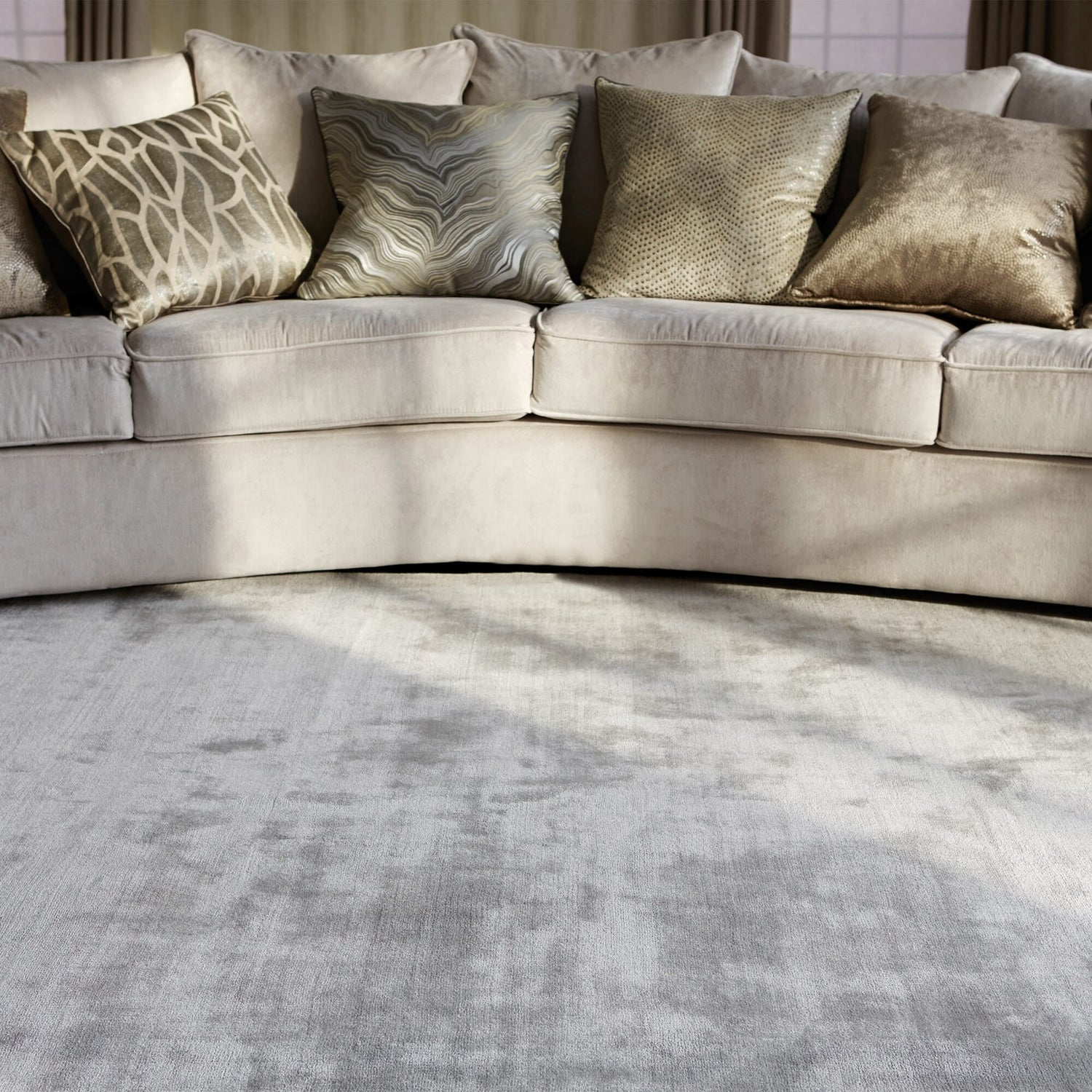 Beige sectional sofa with patterned cushions on a textured gray rug.
