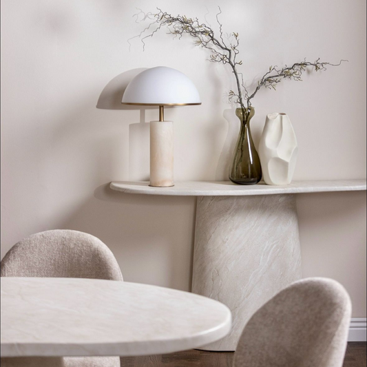 Modern dining area with marble table, chairs, and decorative elements.