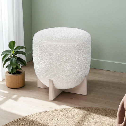 White textured stool next to a potted plant on a wooden floor with a green wall in the background