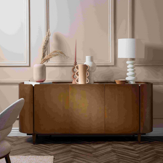 Wooden console table with decorative items in a room with a mirror and lamp.