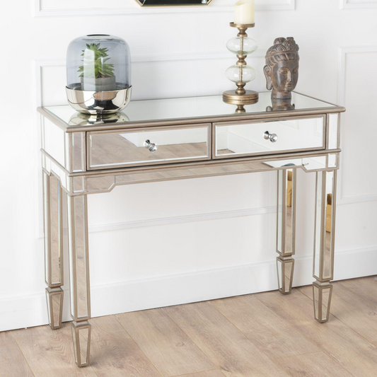 Decorative console table with mirror and decorative items against a white wall.