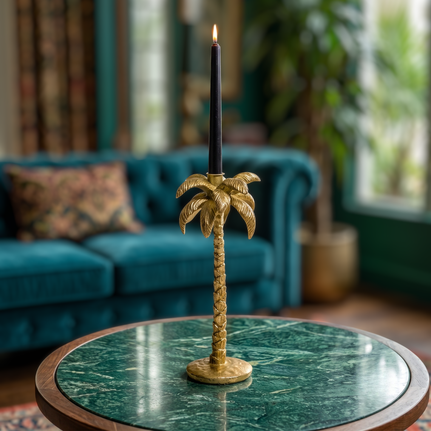 A brass palm tree candlestick holder with a black taper candle, displayed on a green marble-top table in a cozy living room setting.