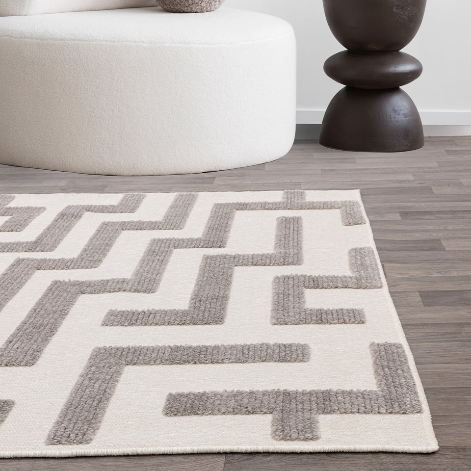 Living room with a geometric patterned rug, white sofa, and decorative side table.