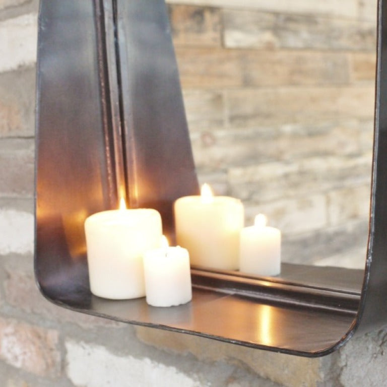 This Industrial Metal Wall Mirror combines style and practicality, perfect for industrial and rustic interiors. Crafted from metal with a dark finish, it adds a sophisticated touch to any room. The small shelf at the bottom offers convenient storage. Its sleek design ensures it complements a variety of decor styles, making it a versatile and functional addition to your home.