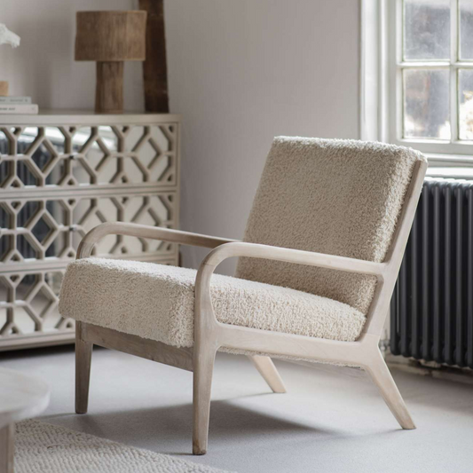 Beige armchair in a room with a decorative side table and window.