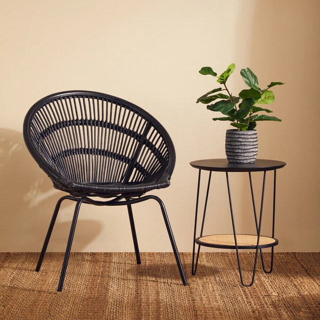 Black wicker chair and side table with a plant against a beige wall.