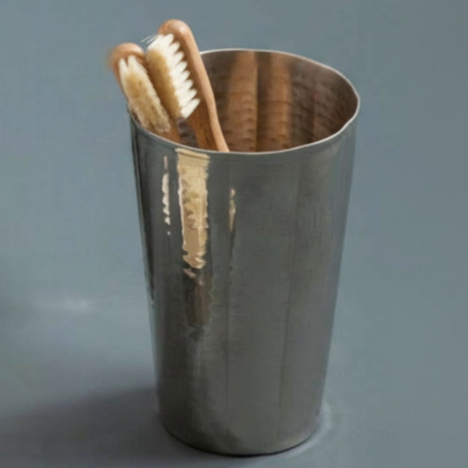 Metal cup with wooden toothbrushes on a gray background
