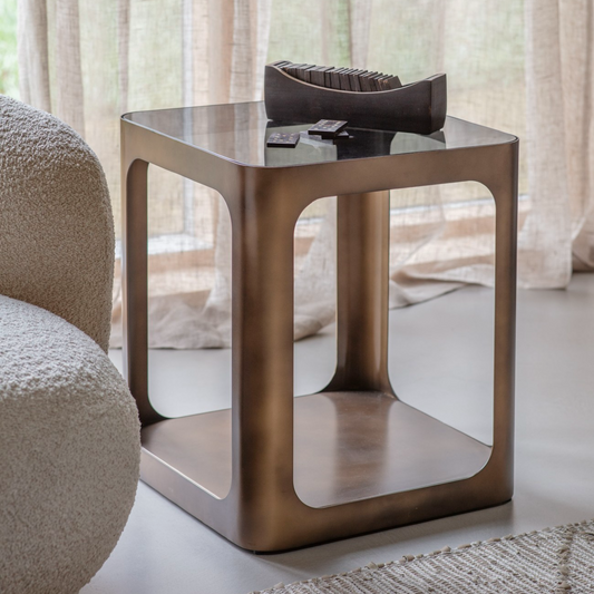 Bronze side table with a glass top in a living room setting