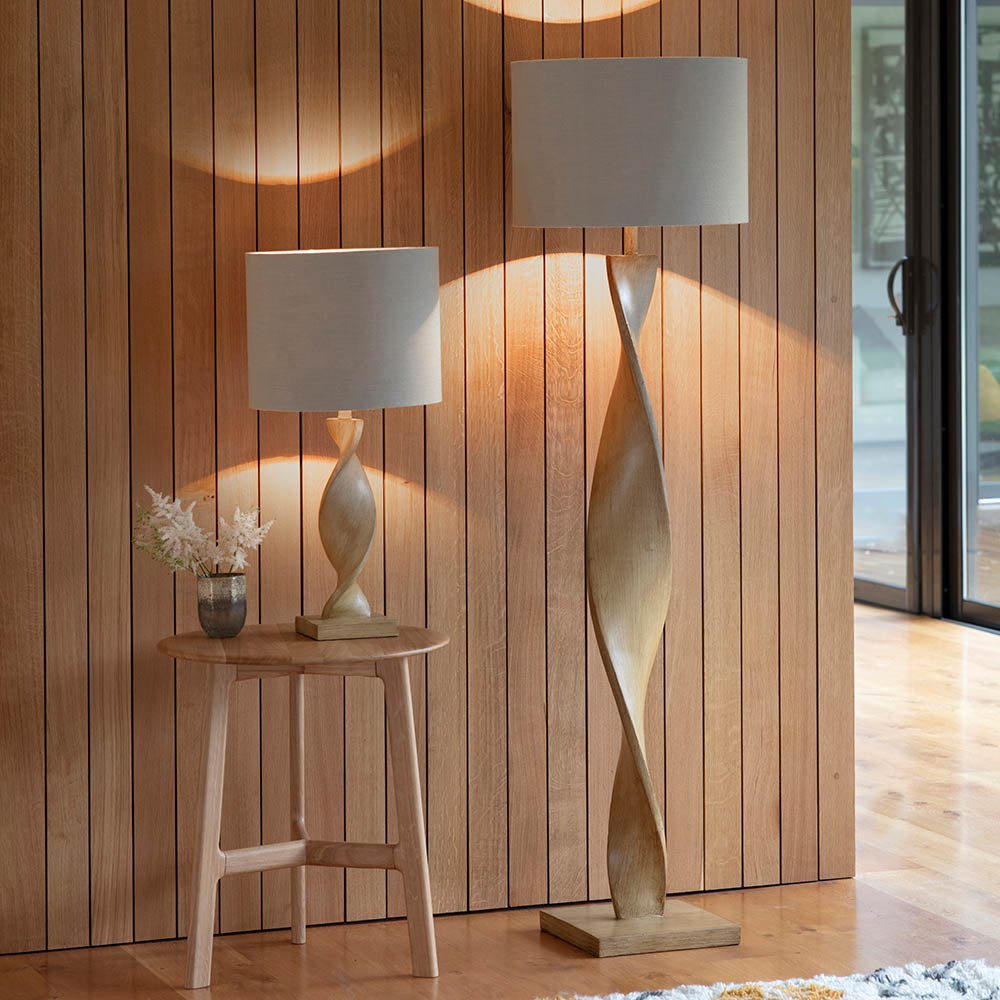 Two lamps, one on a small table and the other standing, against a wooden paneled wall.