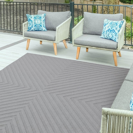 Two chairs with gray cushions and blue patterned pillows on a patio with a gray outdoor rug.