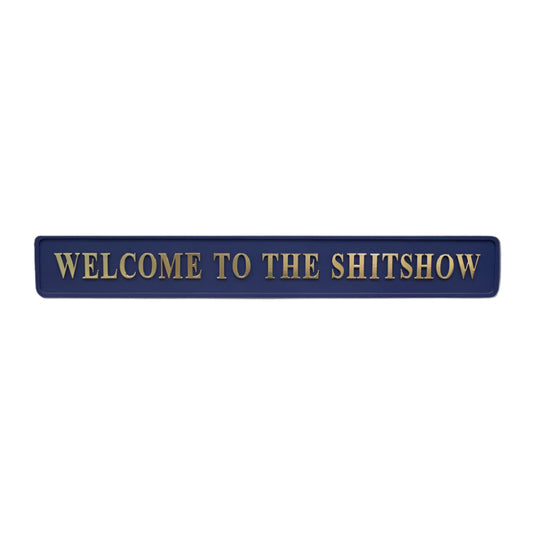 Blue wooden sign with gold text reading 'welcome to the shit show'