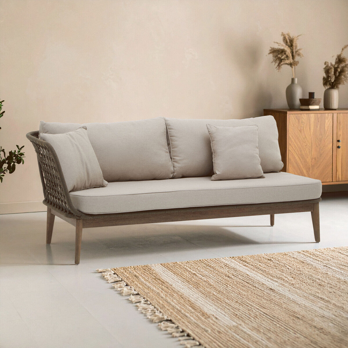 Gray sofa with wooden frame in a room with a wooden cabinet and decorative plants.