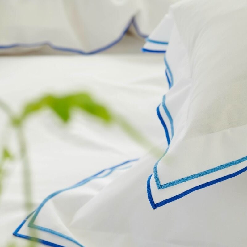 White pillows with blue trim on a blurred green background
