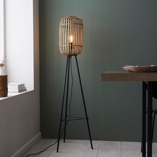Woven floor lamp with black metal base in a room with a table and window.