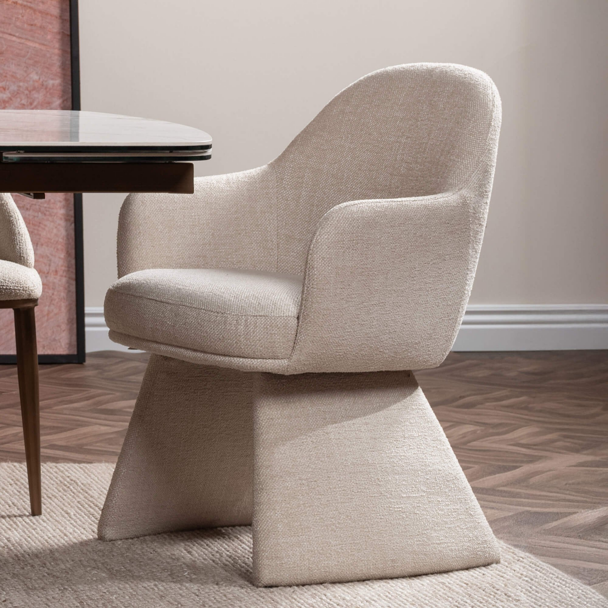 Beige armchair in a room with a table and wall art