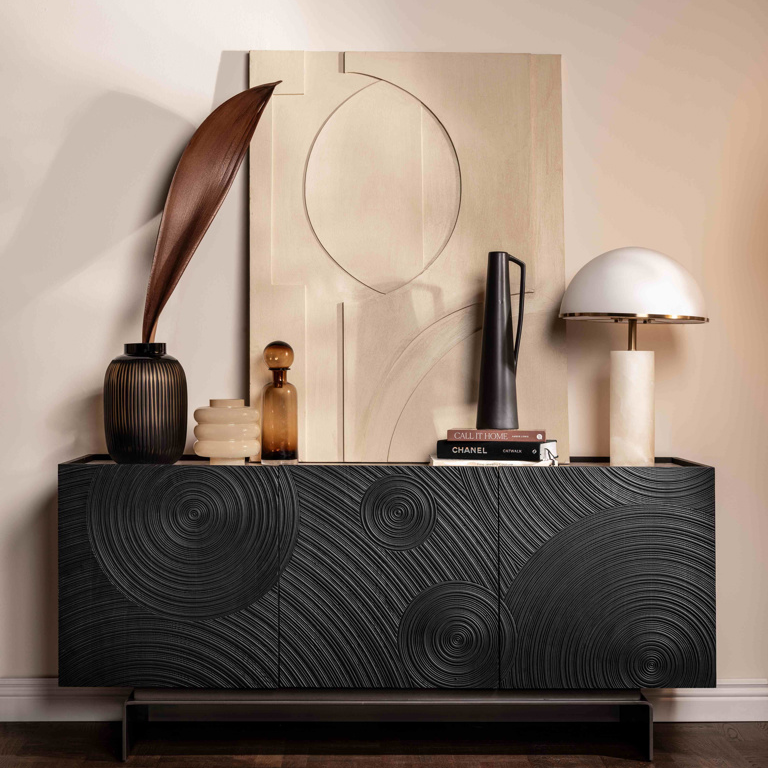 Modern black textured sideboard with decorative items against a beige wall.
