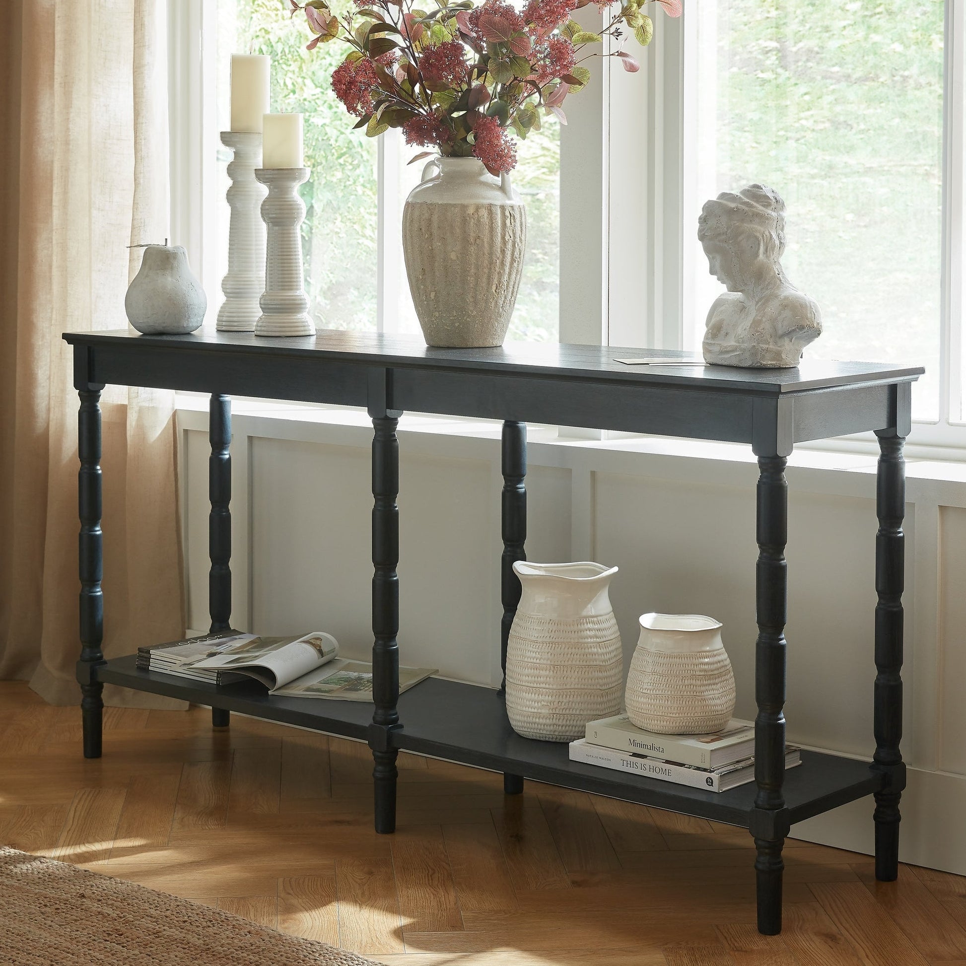 Console table with decorative items in a bright room with large windows.