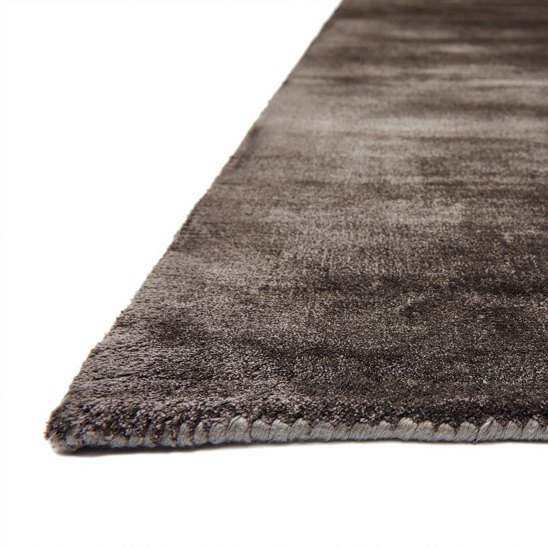 Close-up of a dark gray textured rug corner on a white background