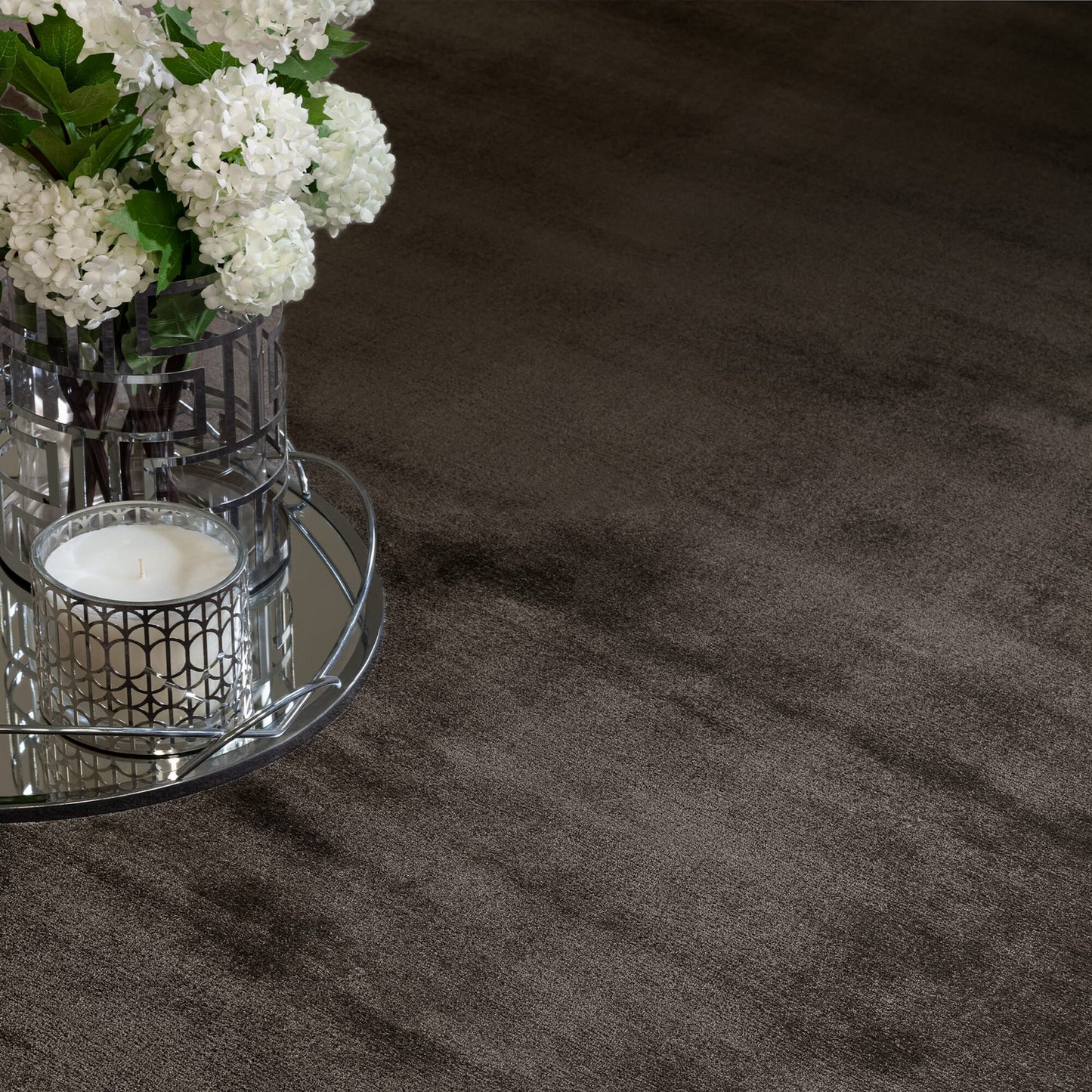 white flowers and a candle on a dark charcoal carpet