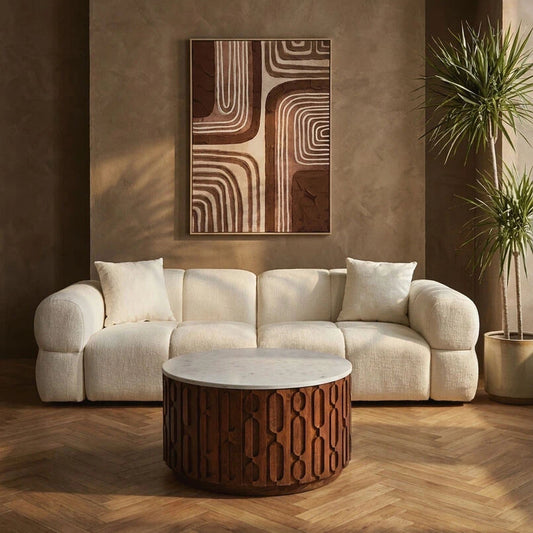 Modern living room with a cream sofa, decorative coffee table, and abstract wall art.