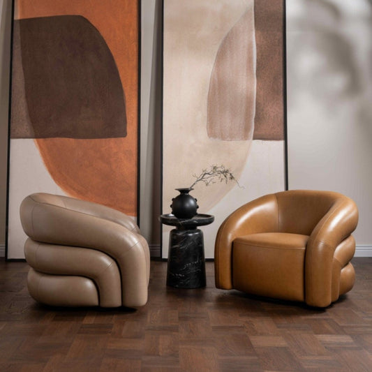 Two brown leather chairs in a room with abstract wall art