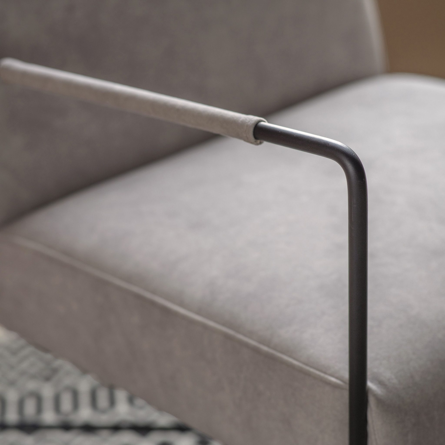 Close-up of a modern chair with a curved armrest and metal leg on a blurred background