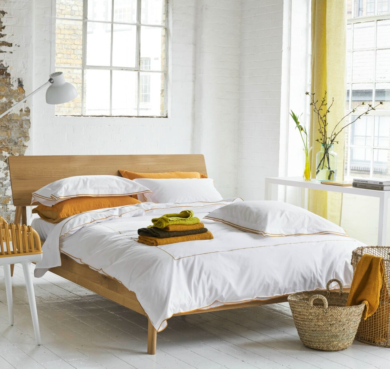 Bedroom with wooden bed, white bedding, and yellow accents.