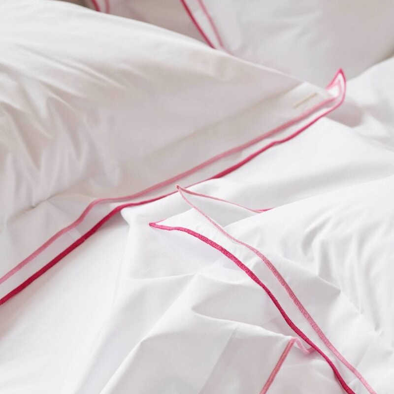 White bedding with fuschia piping on a soft focus background