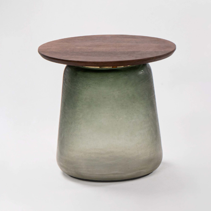 Small round table with wooden top and green glass base on a white background